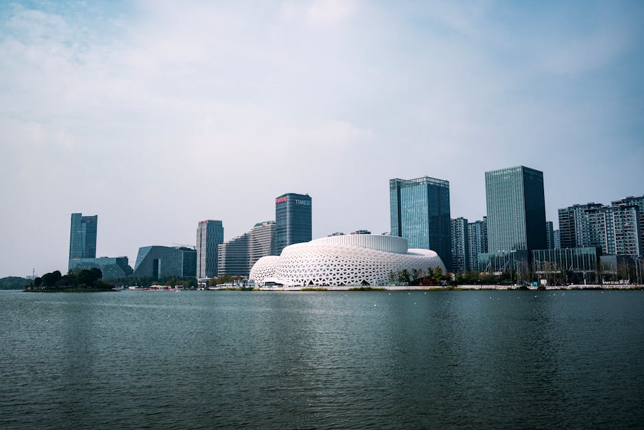 A modern city skyline with unique architecture and waterfront view under a clear blue sky.
