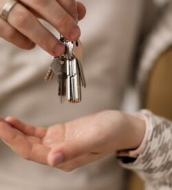 A close-up photograph of hands exchanging keys, symbolizing new home ownership.